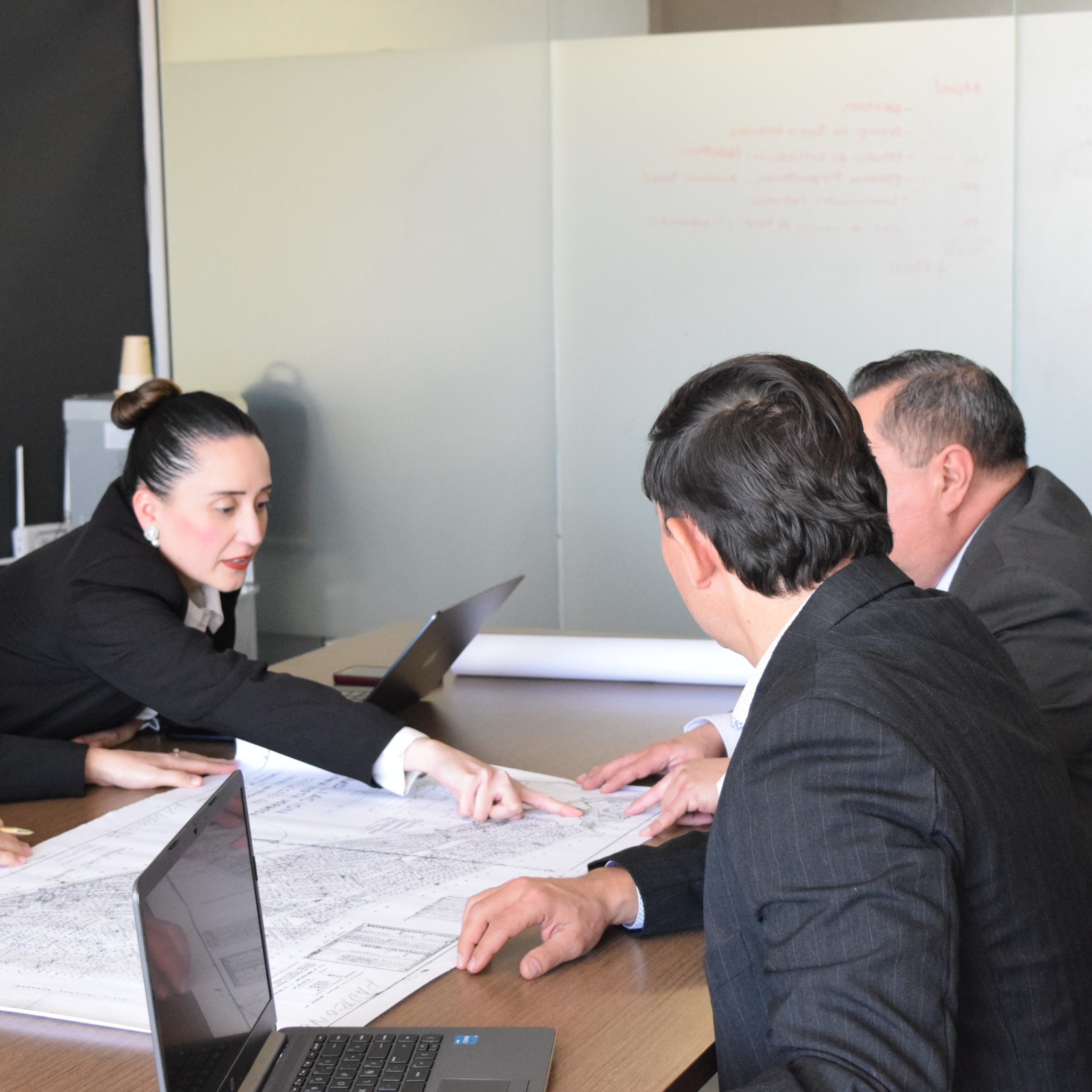 Profesionales en reunión analizando planos urbanos y estrategias de planeación. Manglar Consultores.