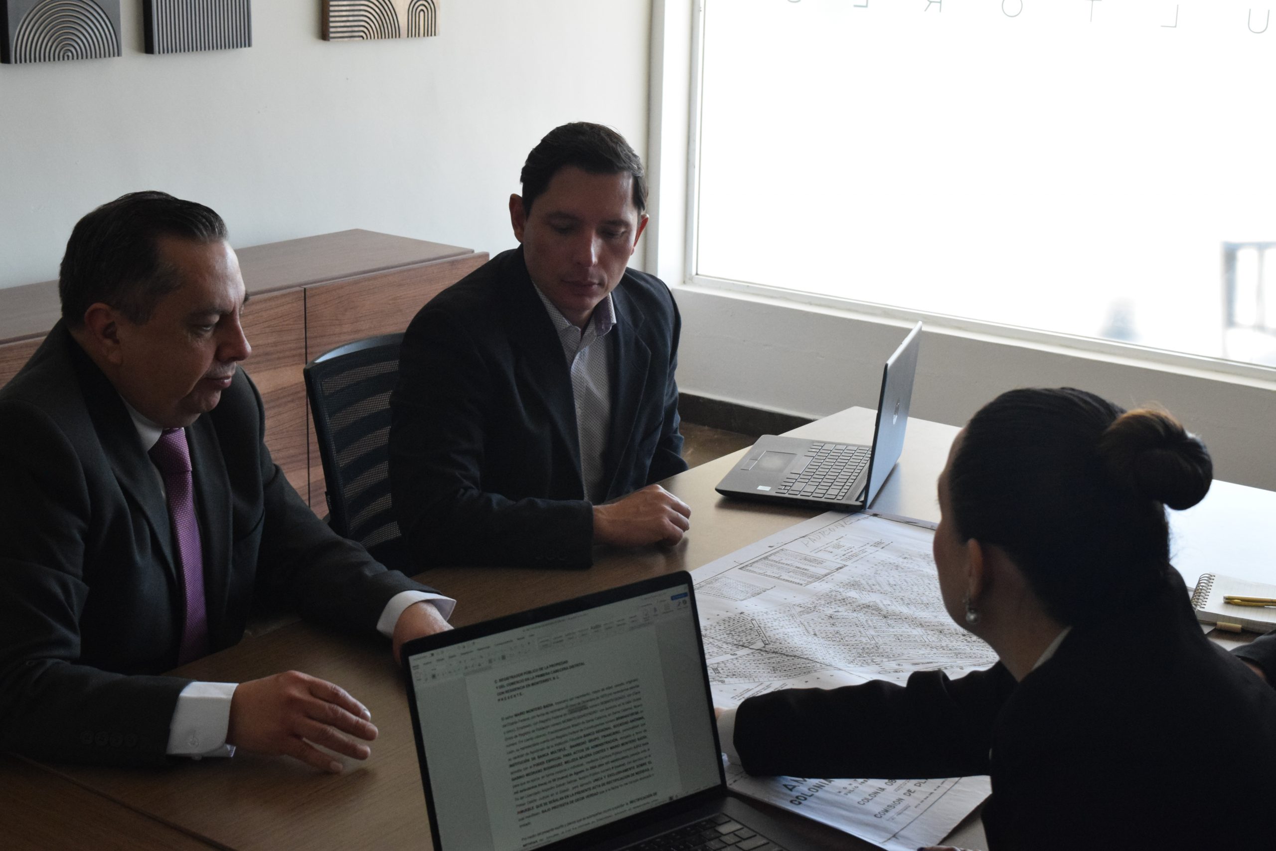 ersonas reunidas en una mesa revisando documentos legales y normativos. Manglar Consultores.